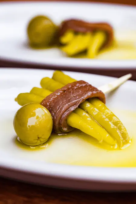 Gilda clásica con anchoa, aceitunas verdes y piparras en un plato.