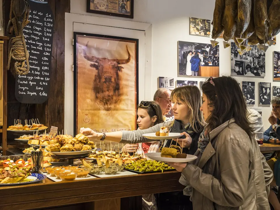 Personas disfrutando de pintxos en una barra.