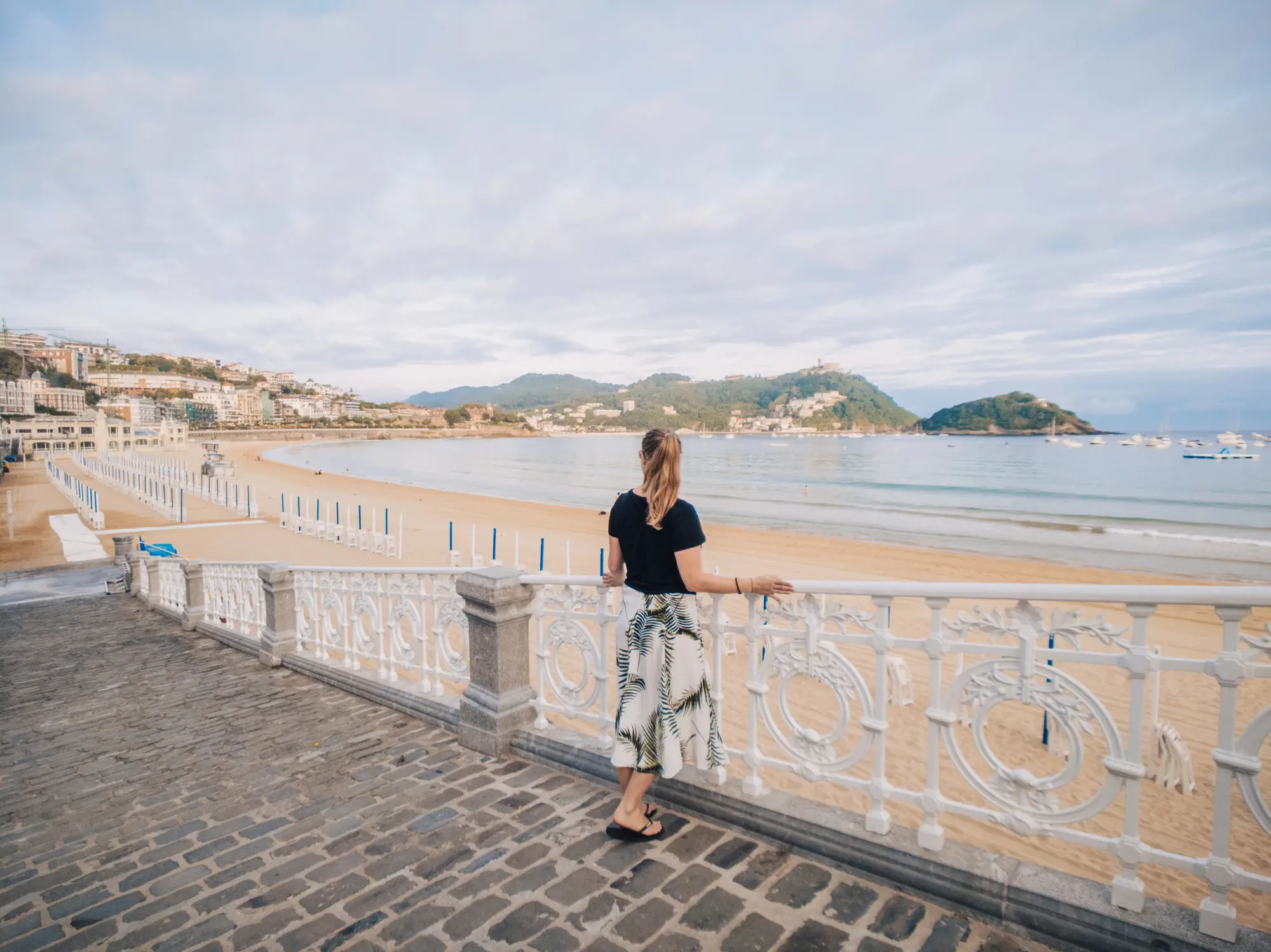 Mujer mirando la playa de la Concha desde la barandilla.
