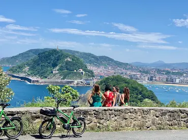 Grupo de amigas descansando tras su paseo en bici, con vistas a la costa de San Sebastián