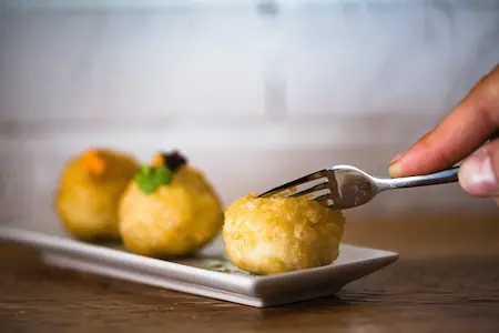 Persona con un tenedor sobre un plato, preparándose para disfrutar la comida.