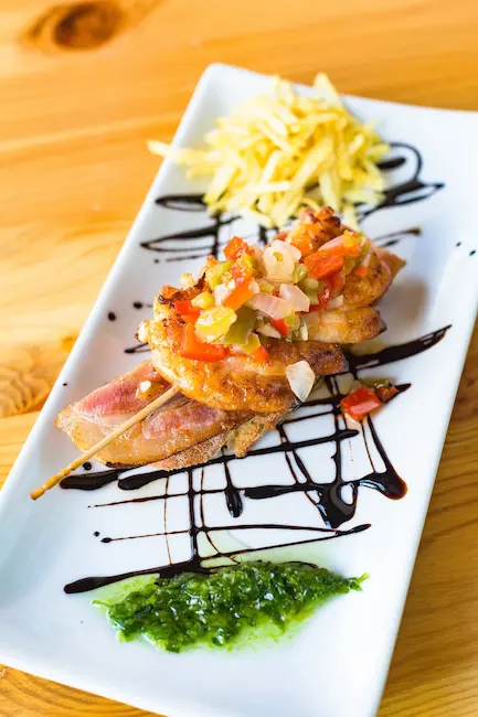 Elegante presentación de un pintxo vasco con salsa y chips en un plato.