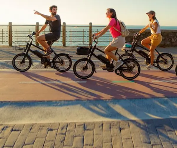 Grupo de personas montando bicicletas en el bidegorri junto al océano, disfrutando del paisaje y el aire fresco.