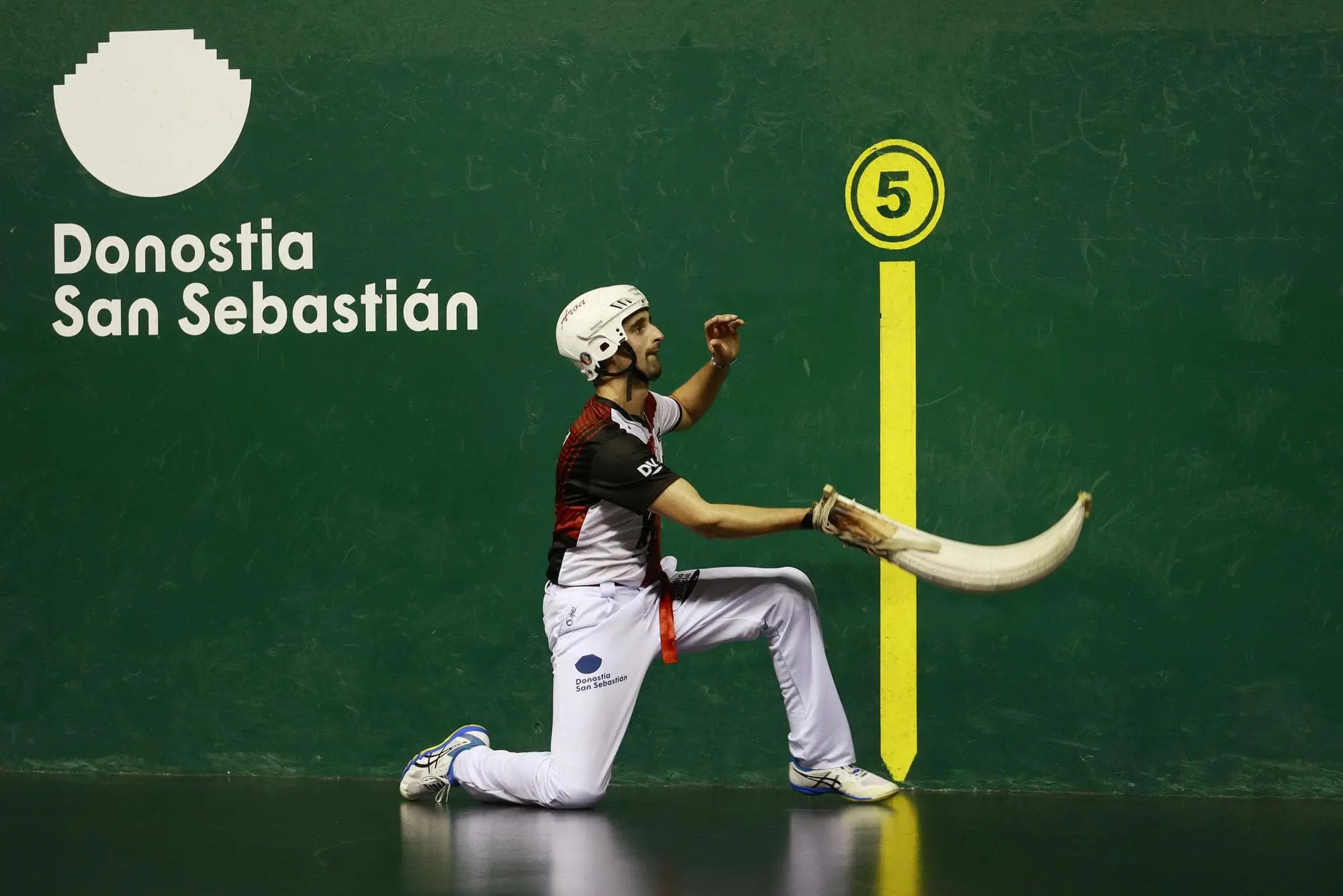 Pelotari playing cesta punta in a fronton.