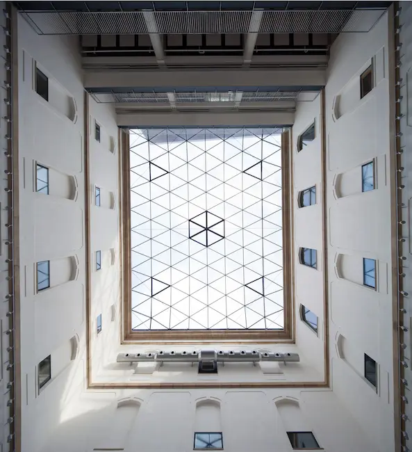 Perspectiva desde el suelo de un edificio, observando el cielo a través de un techo de cristal.