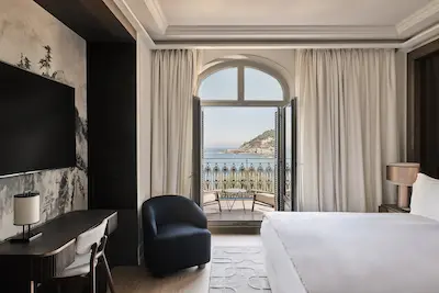 Elegante habitación de hotel con gran balcón y vistas a la playa
