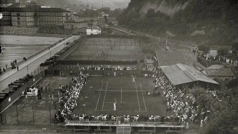 Foto antigua de la pista de tenis en Ondarreta, con espectadores observando un partido.
