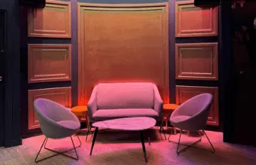 Sala con asientos y mesa baja iluminados con luz rosada