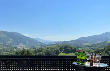 Terraza con vistas a la montaña y una pequeña mesa con bebidas a un lado