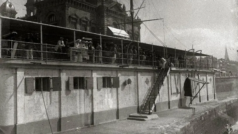 Foto antigua de personas mirando hacia el mar desde el Real Club Naútico de San Sebastián.