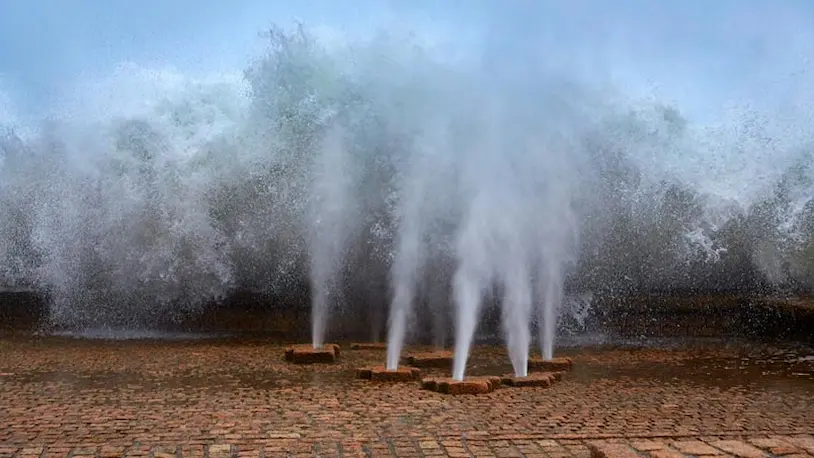 Agua saliendo de las chimeneas en el suelo de la plaza donde se encuentran las esculturas de Peine del Viento.