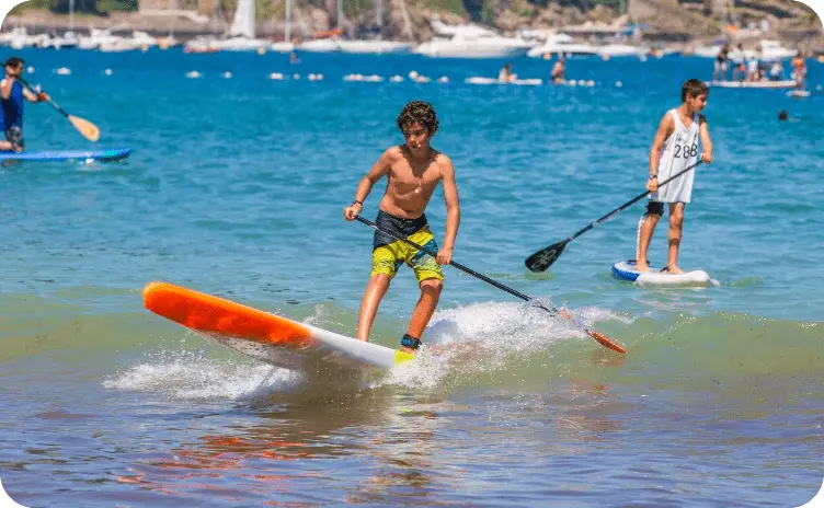 Niños haciendo pádel surf en la playa