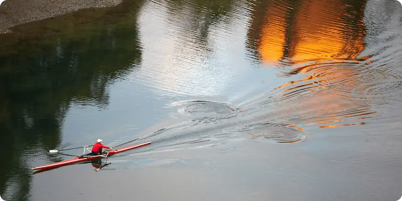 Persona remando en kayak de doble remo sobre el agua