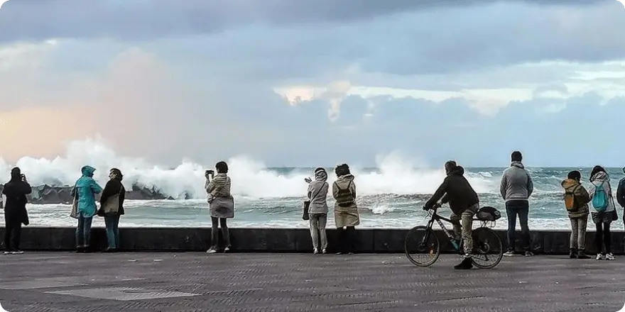 Personas en el paseo de Donosti viendo las olas romper.