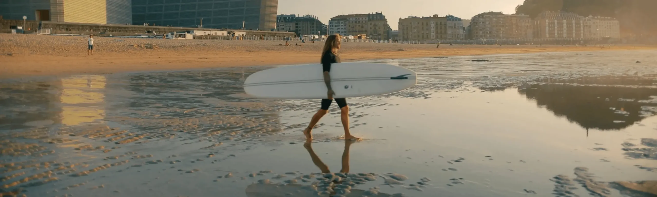 Surfer walking toward the sea with board under arm