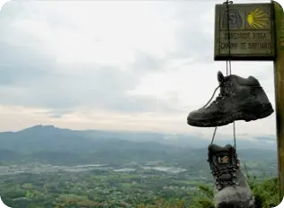 Señal del Camino de Santiago con botas colgando