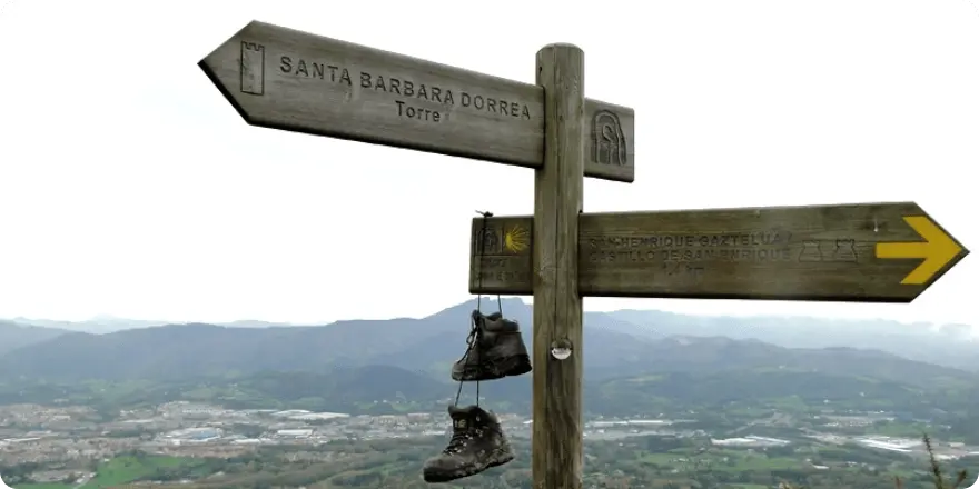 Señal del Camino de Santiago con botas colgando