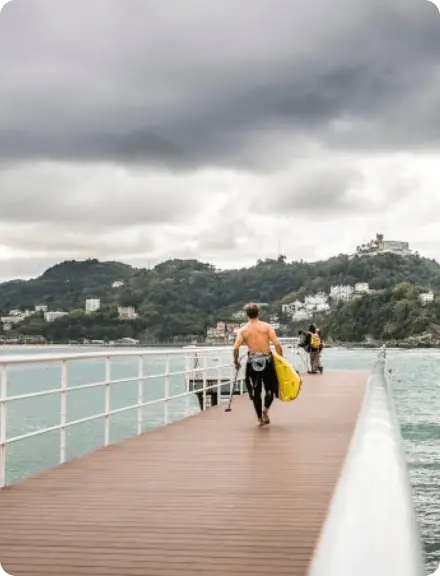 Hombre caminando por el pantalán con su tabla de surf