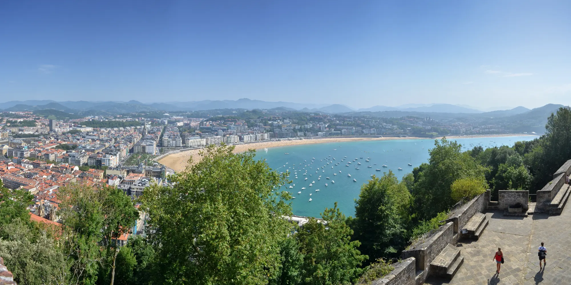 Vista panorámica de San Sebastián desde el Monte Urgull, con la Playa de la Concha y barcos en la bahía.